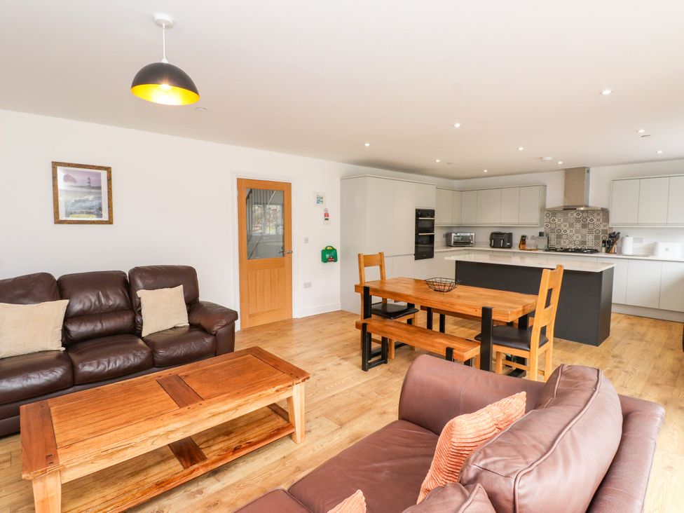 A living room with a sofa and dining area at 95 Cae America Llanfairfechan