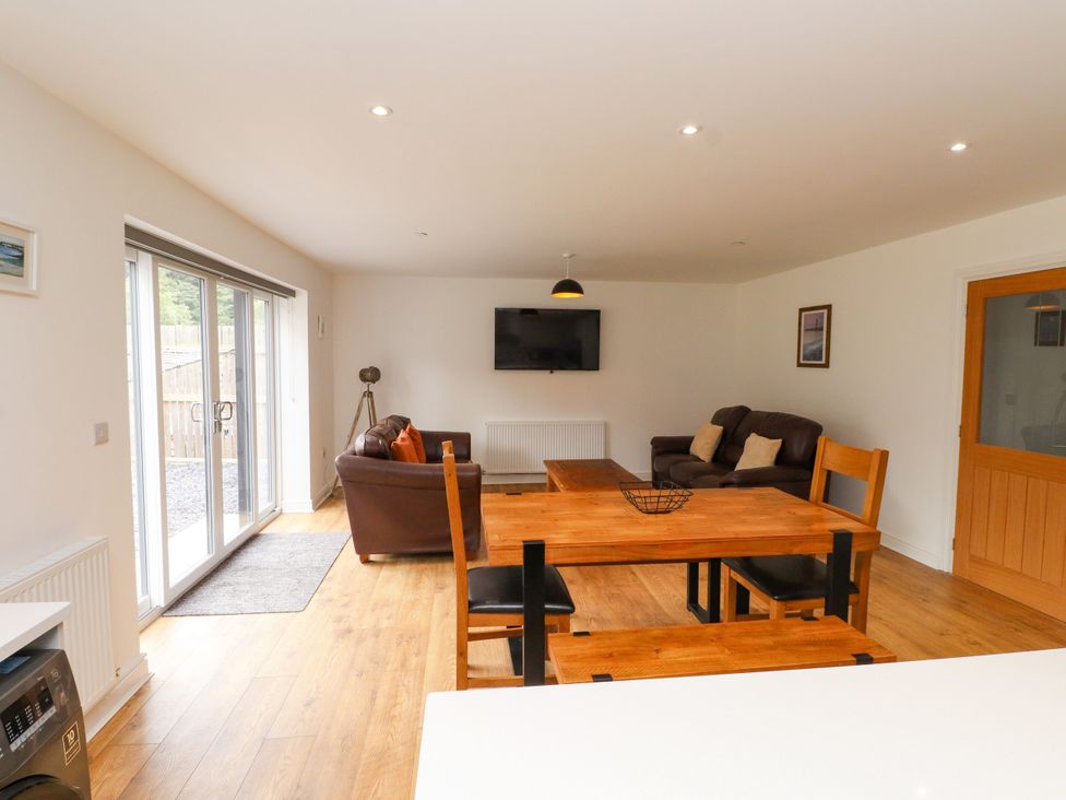 A living room with a sofa and dining area at 95 Cae America in Llanfairfechan