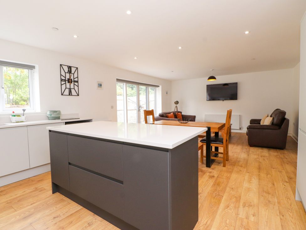 A kitchen with an island and dining area at 95 Cae America in Llanfairfechan