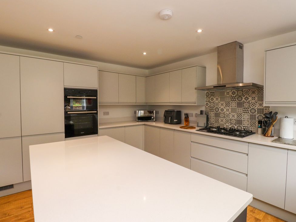 A kitchen with cabinets, oven, microwave and gas stove at 95 Cae America Llanfairfechan