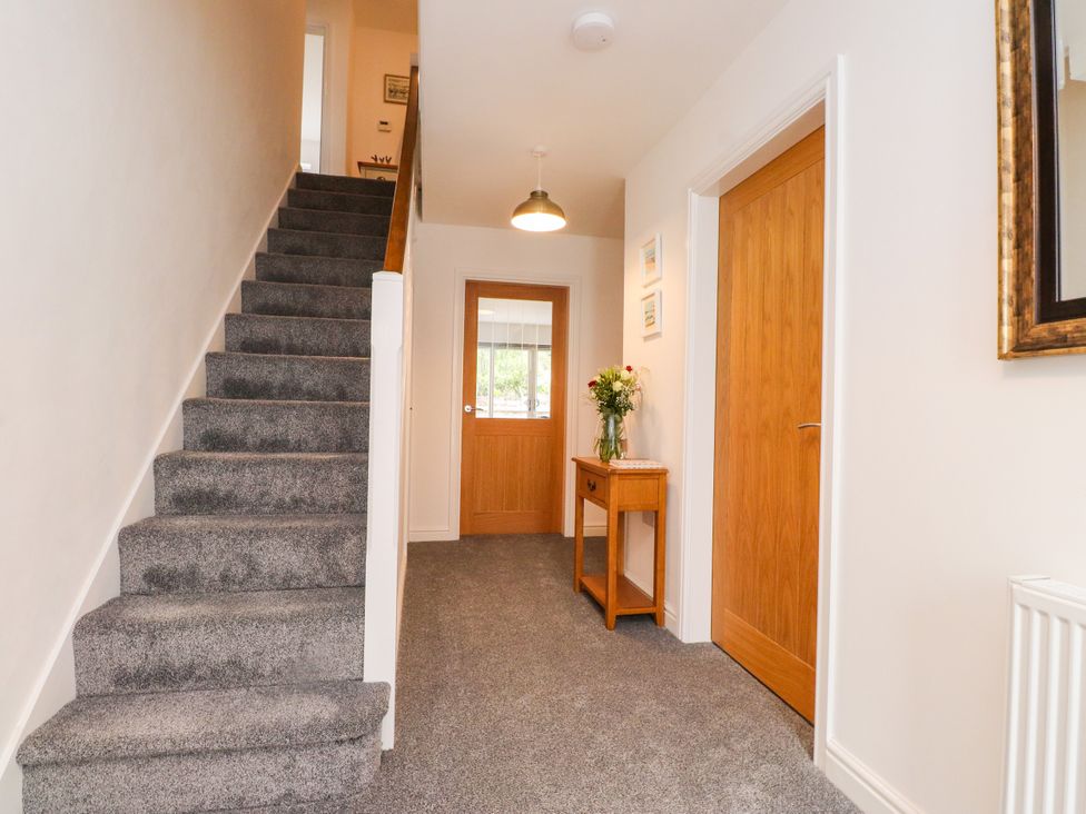 A hallway with a staircase and wooden table at 95 Cae America in Llanfairfechan