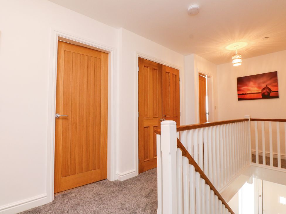 A hallway with multiple doors and a light fixture at 95 Cae America in Llanfairfechan