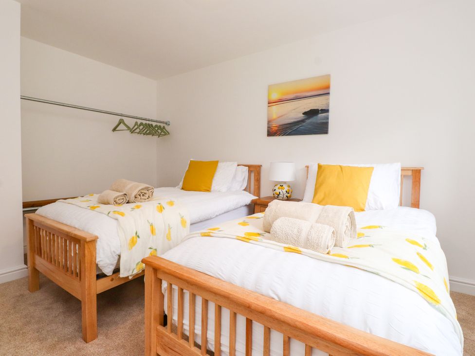 A bedroom with two beds and a painting at 95 Cae America in Llanfairfechan