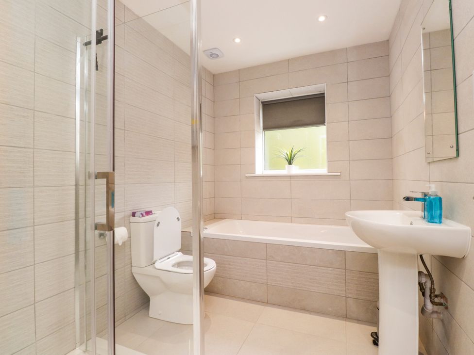 A bathroom with a toilet, bathtub, sink and shower at 95 Cae America in Llanfairfechan
