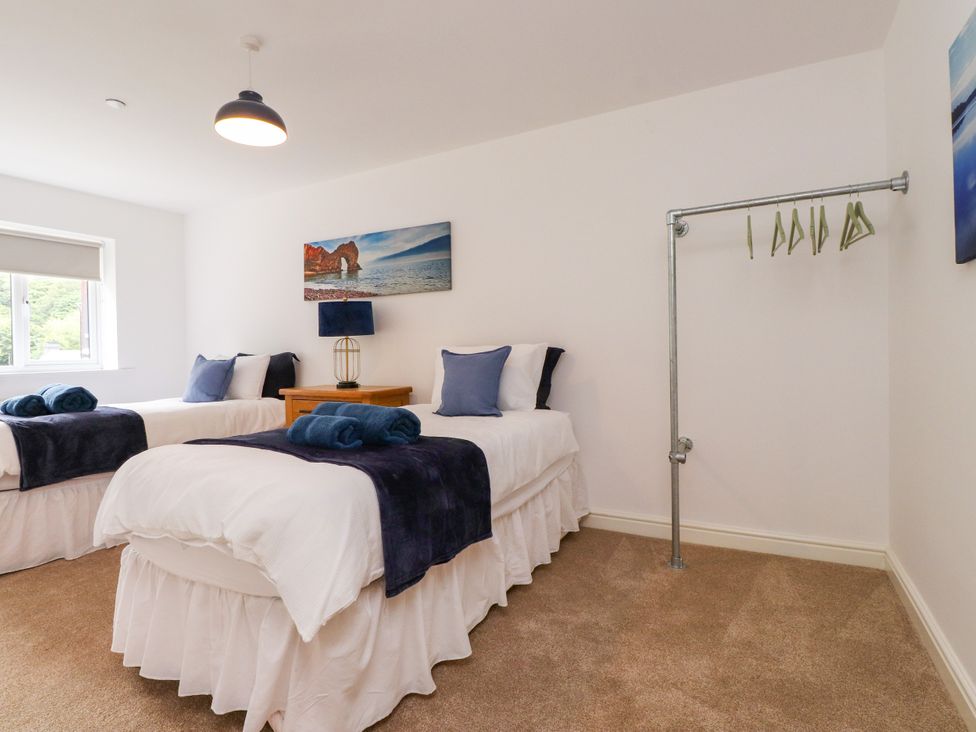 A bedroom with two beds and a clothing rack at 95 Cae America in Llanfairfechan