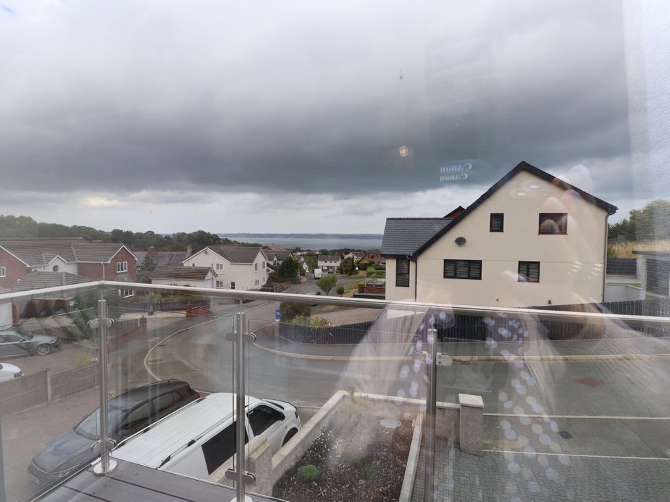 A view of houses and a road with water in the background at 95 Cae America Llanfairfechan