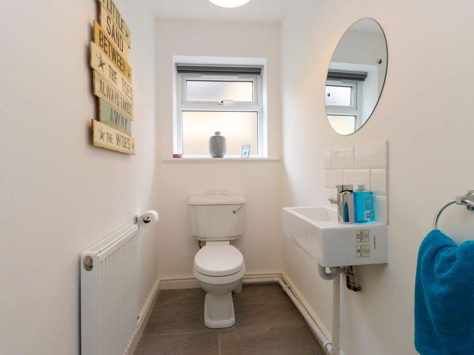 A bathroom with a toilet, sink, and mirror at 95 Cae America in Llanfairfechan