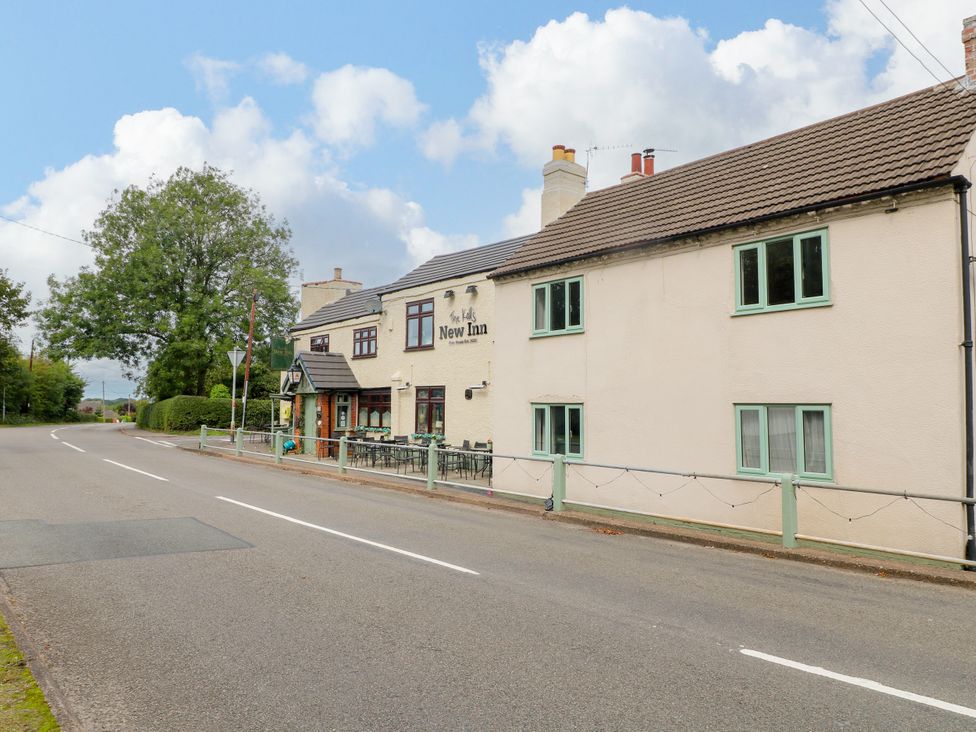 A pub exterior with signage and seating at New Inn in Coalville