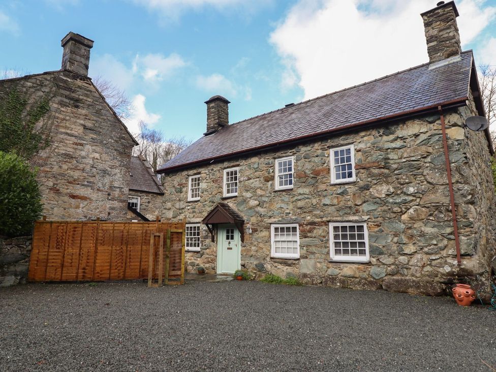 An outdoor view of a stone house with a wooden fence at Cader Cottage Dolgellau