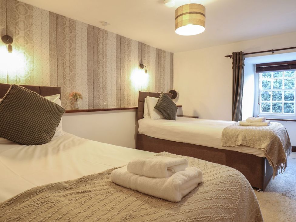 A bedroom with two beds and a window at Cader Cottage in Dolgellau