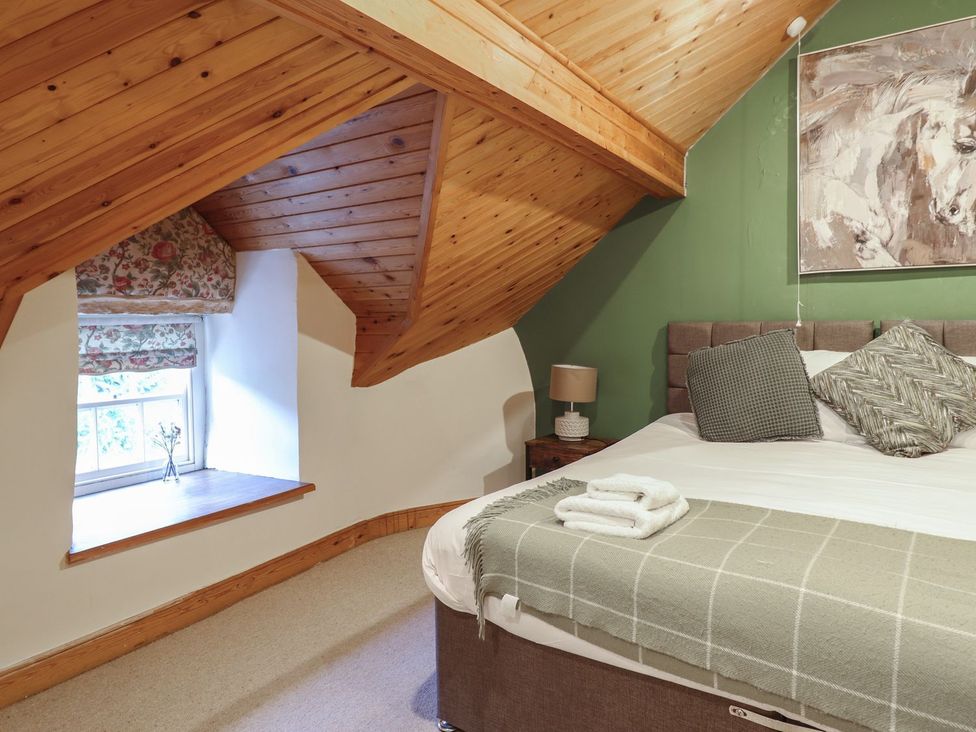 A bedroom with a bed, window, and artwork at Cader Cottage in Dolgellau