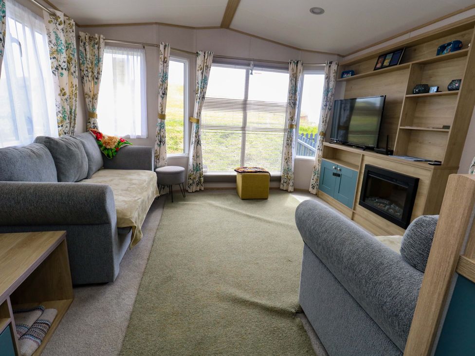 A living room with a sofa and television at Caravan A7 in Bridport