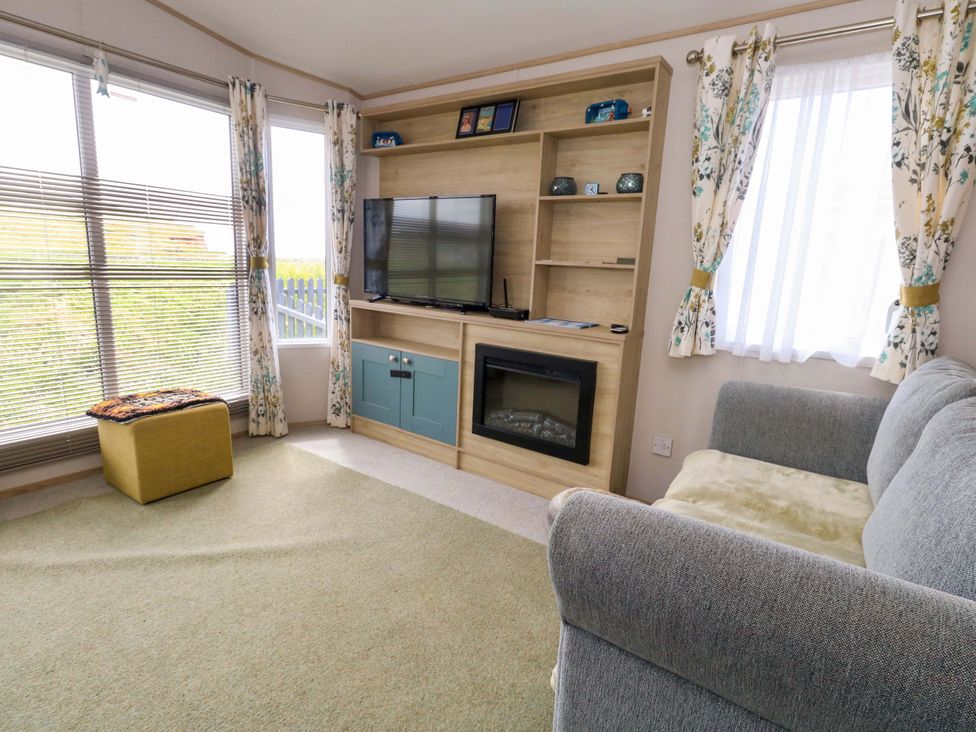 A living room with a sofa and television at Caravan A7 Bridport
