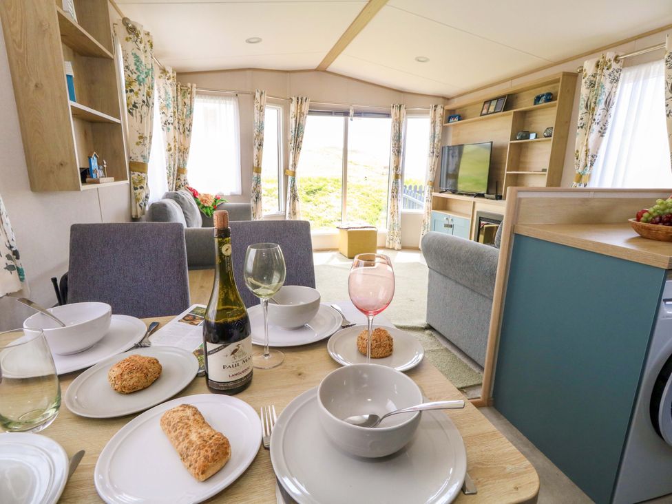 A dining table with dishes and drinks in a living room at Caravan A7 in Bridport