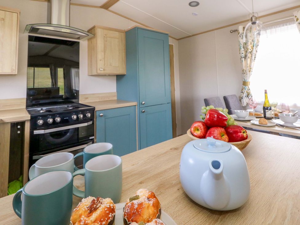 A kitchen with a stove, kettle, cups, and fruit at Caravan A7 in Bridport