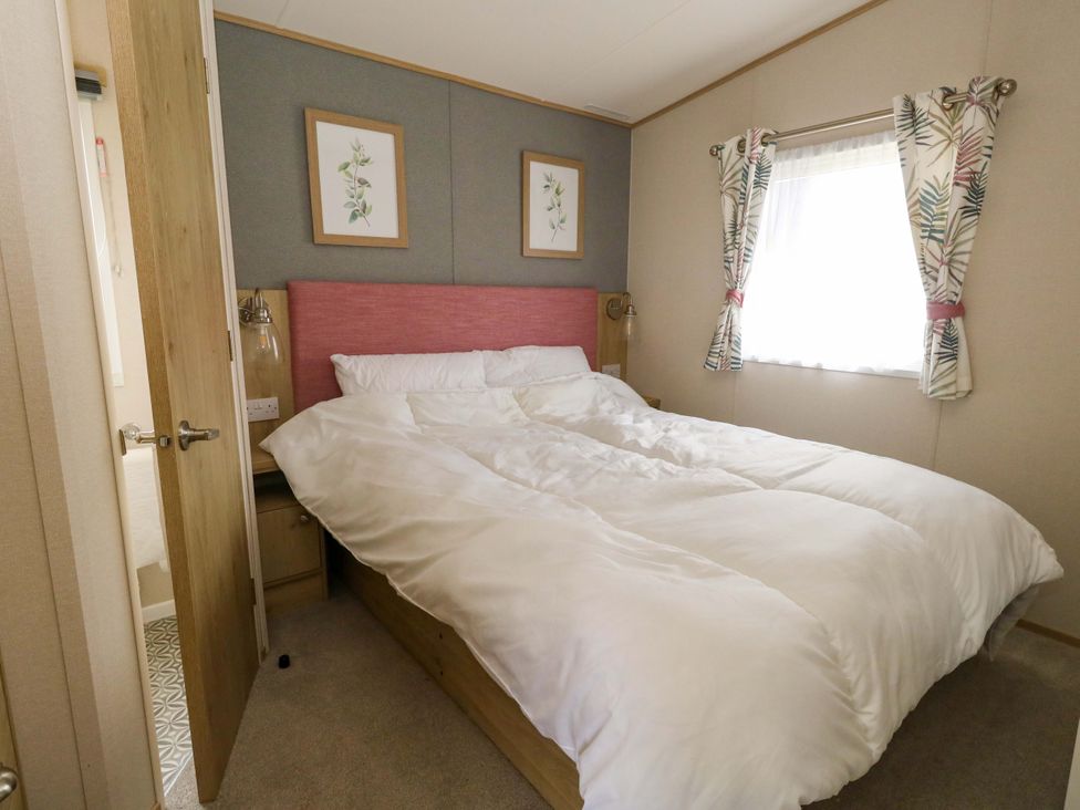A bedroom with a bed and decorative pictures at Caravan A7 in Bridport