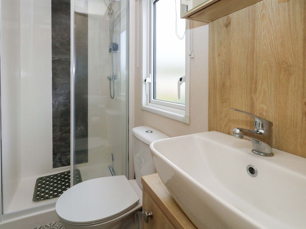 A bathroom with a shower, toilet, and sink at Caravan A7 Bridport