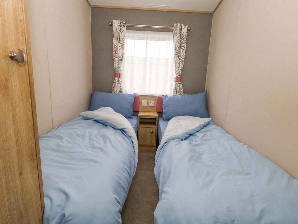 A bedroom with two single beds and a window at Caravan A7 in Bridport