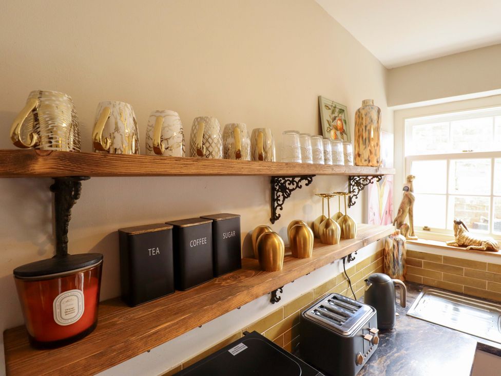 A kitchen with shelves containing mugs, glasses, and canisters at 35 Wrawby Street Brigg