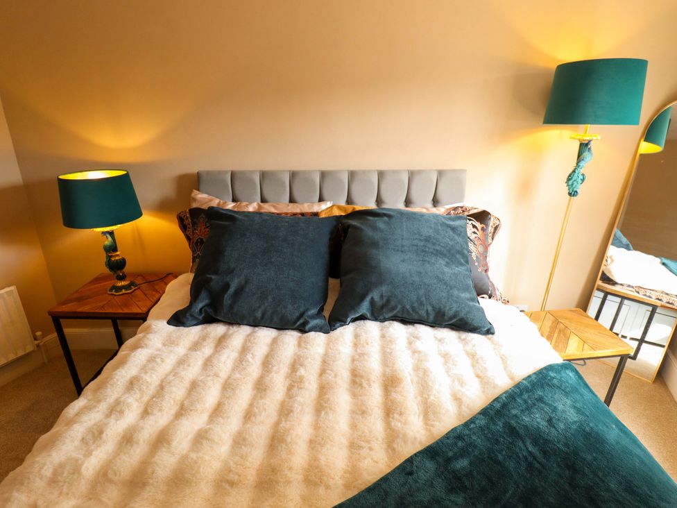 A bedroom with a bed, pillows, lamp, and a mirror at 35 Wrawby Street, Brigg