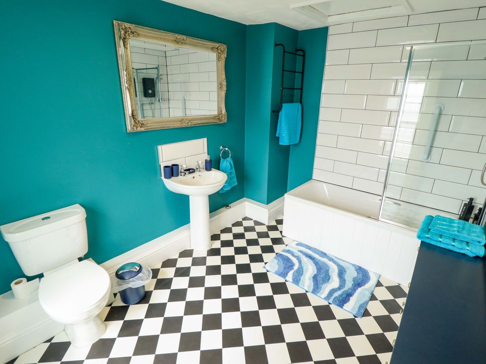 A bathroom with a sink, toilet, mirror, and bathtub at 35 Wrawby Street in Brigg