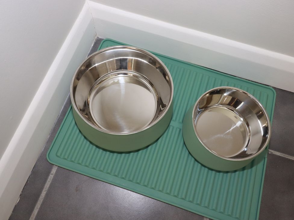 Two metal pet bowls on a mat in a kitchen at 67 Manor Villas Newquay