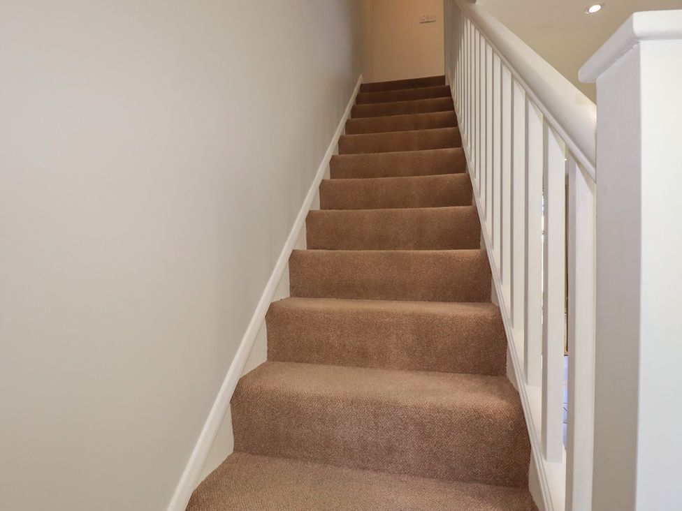 A staircase with carpet steps and a handrail at 67 Manor Villas in Newquay