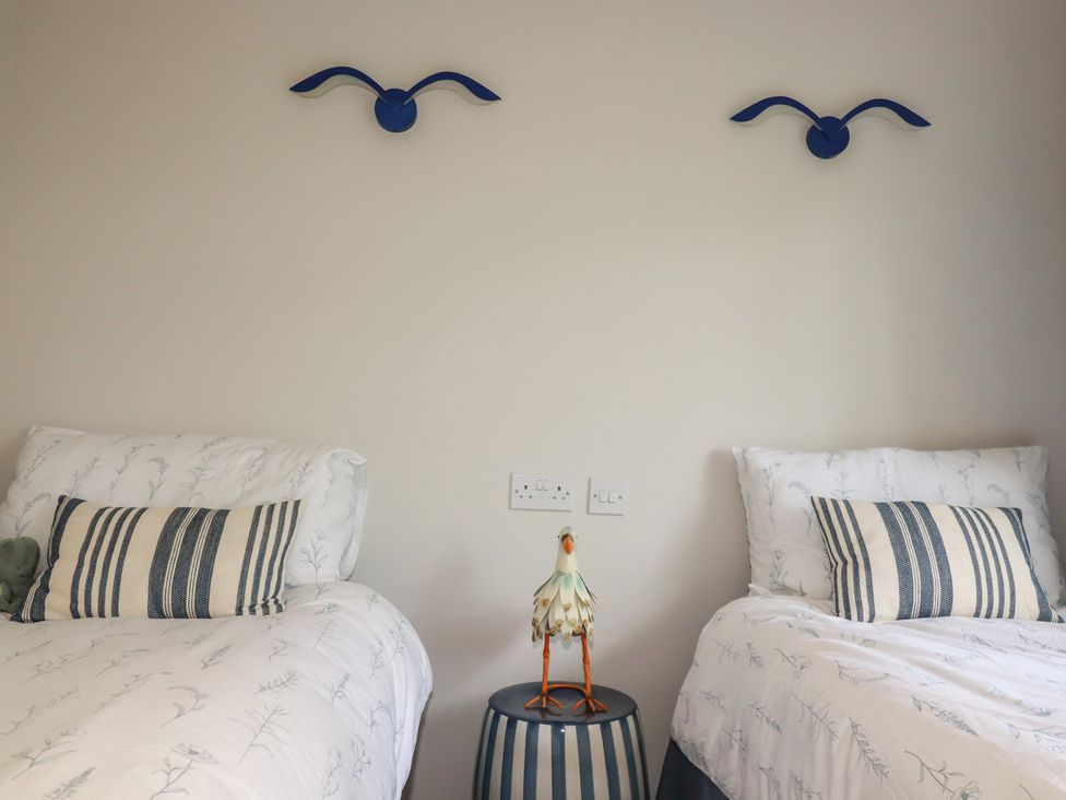 A bedroom with two beds and a decorative item on a nightstand at 67 Manor Villas in Newquay