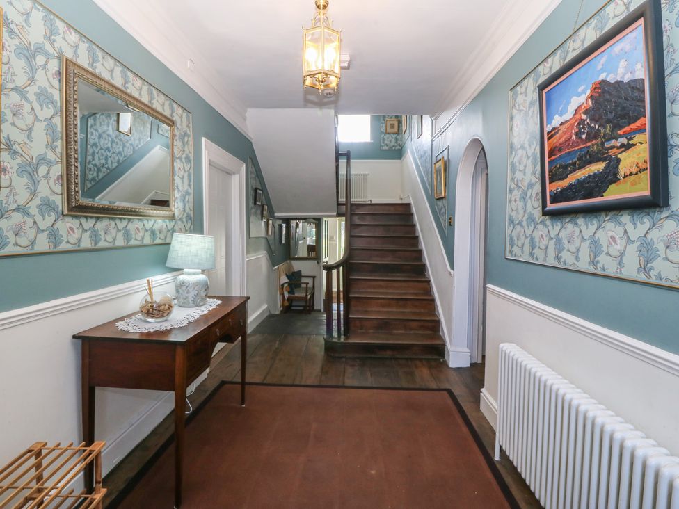 A hallway with a staircase, lamp and mirror at Tan y Gader in Dolgellau