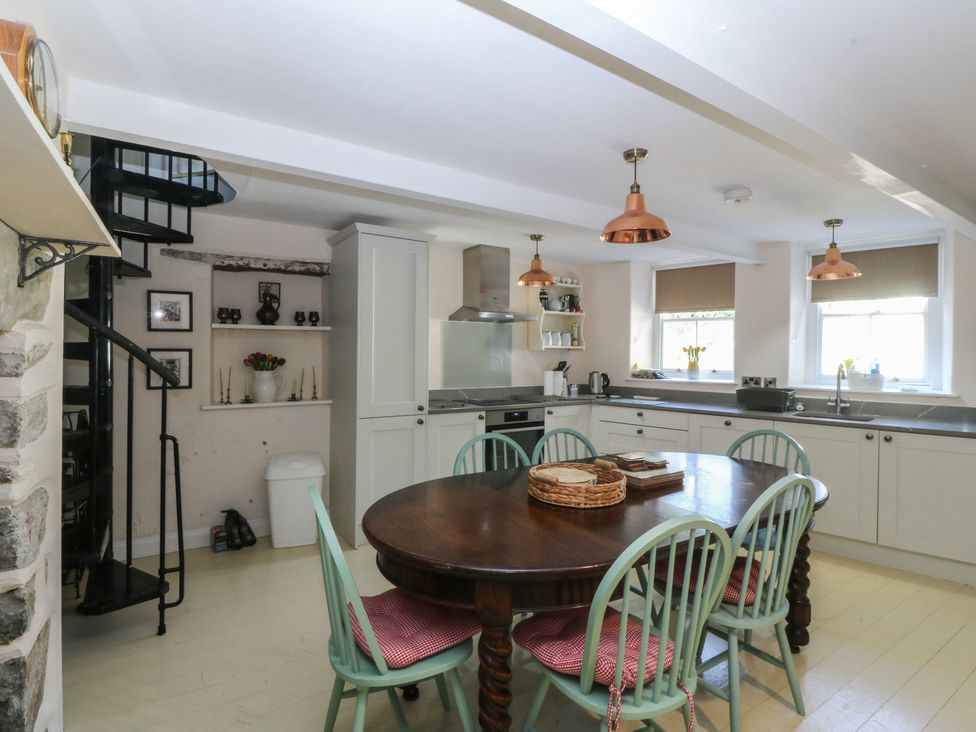A kitchen with a dining table and spiral staircase at Tan y Gader in Dolgellau