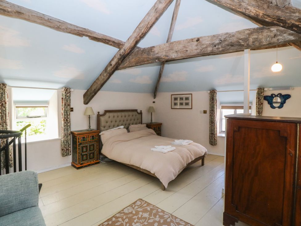 A bedroom with a bed, nightstands, and a window at Tan y Gader in Dolgellau