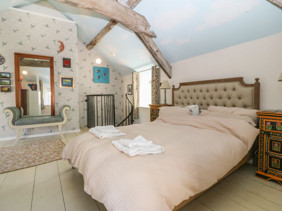A bedroom with a bed and mirror at Tan y Gader in Dolgellau