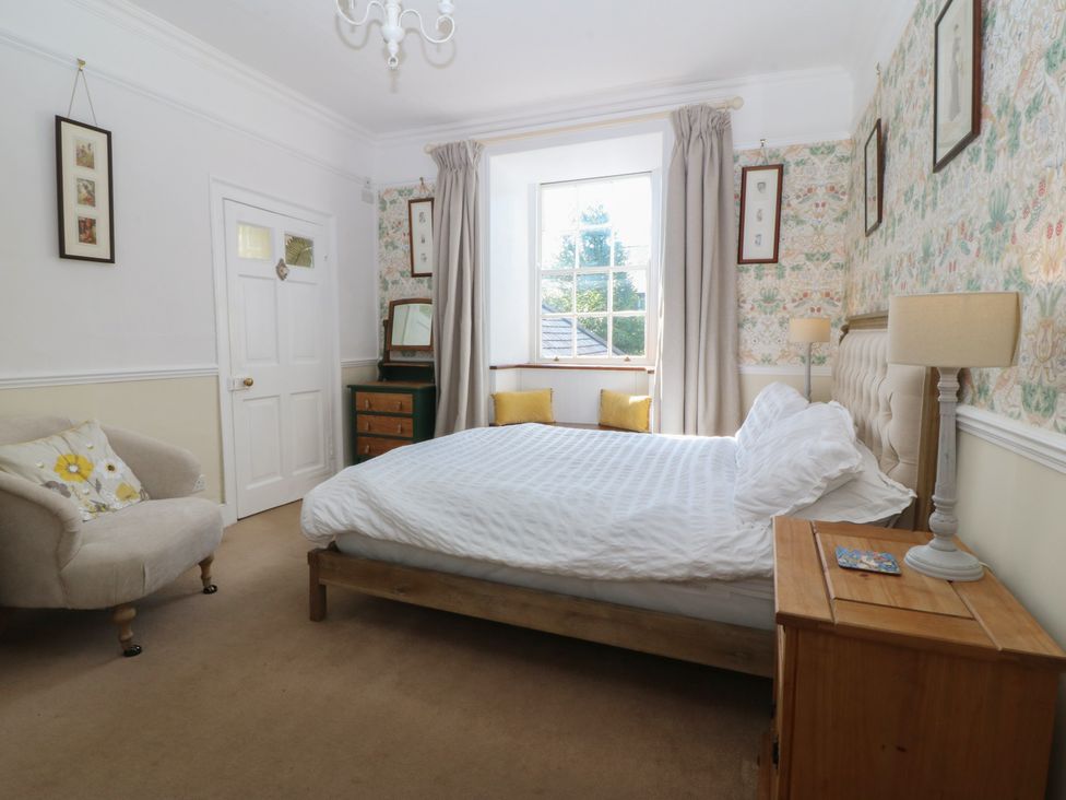 A bedroom with a bed and a chair at Tan y Gader in Dolgellau