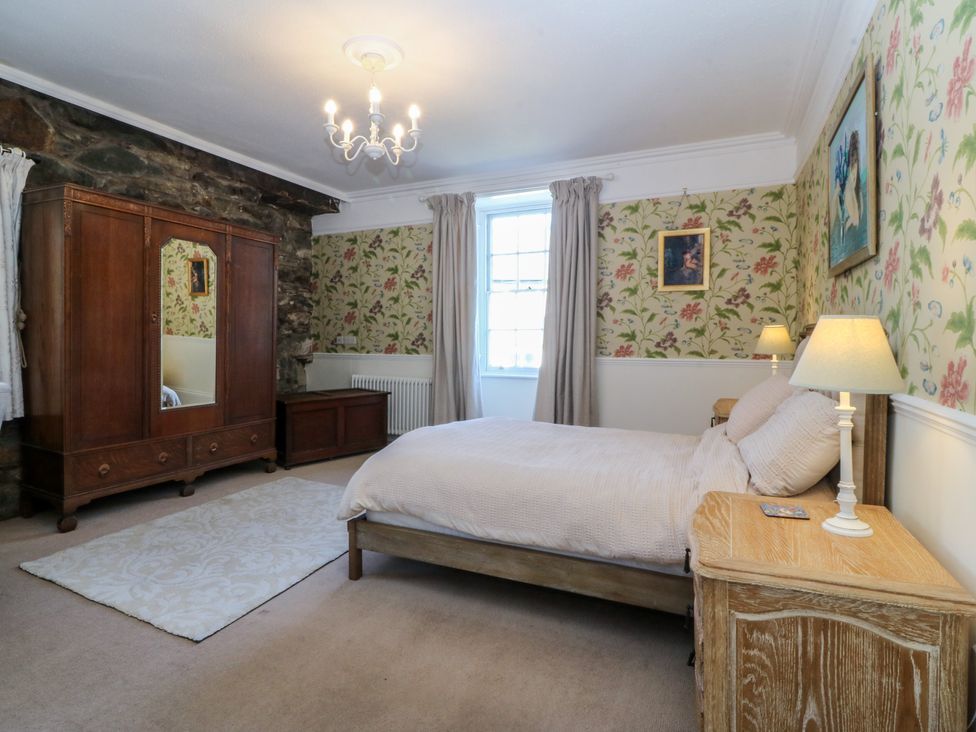 A bedroom with a bed and wardrobe at Tan y Gader in Dolgellau