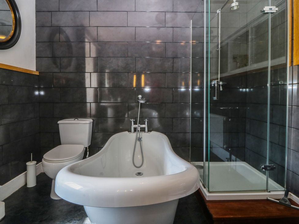 A bathroom with a bathtub, toilet, and shower at Tan y Gader in Dolgellau