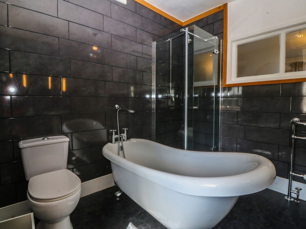 A bathroom featuring a bathtub, toilet, and shower at Tan y Gader in Dolgellau