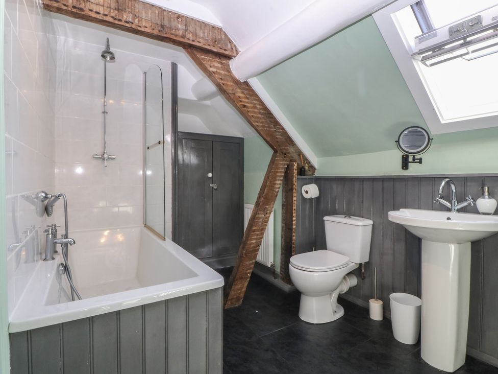 A bathroom with a bath tub, shower, toilet, and sink at Tan y Gader in Dolgellau