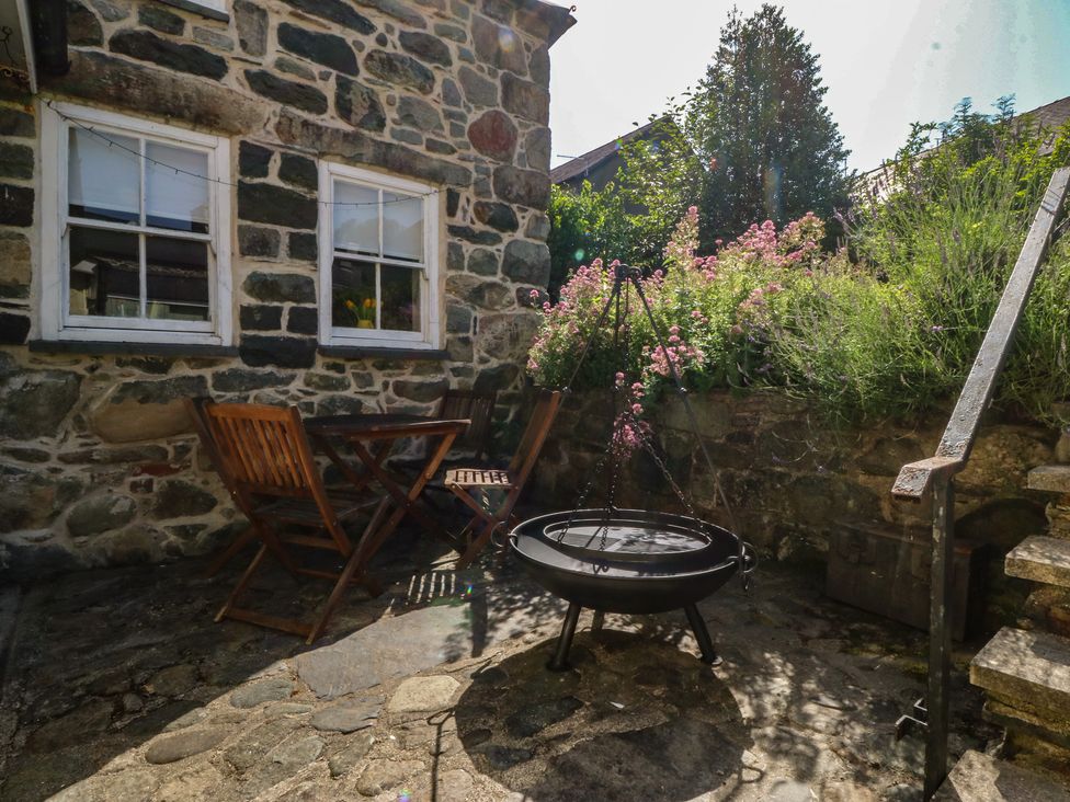 A garden area with a table and chairs next to a fire pit at Tan y Gader in Dolgellau