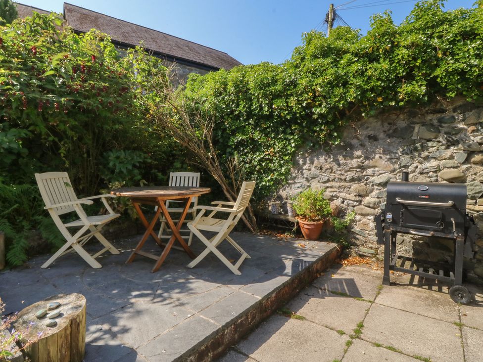 A garden with a table and chairs next to a barbecue at Tan y Gader in Dolgellau