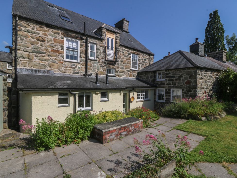 A house with a stone wall, patio, and garden at Tan y Gader in Dolgellau