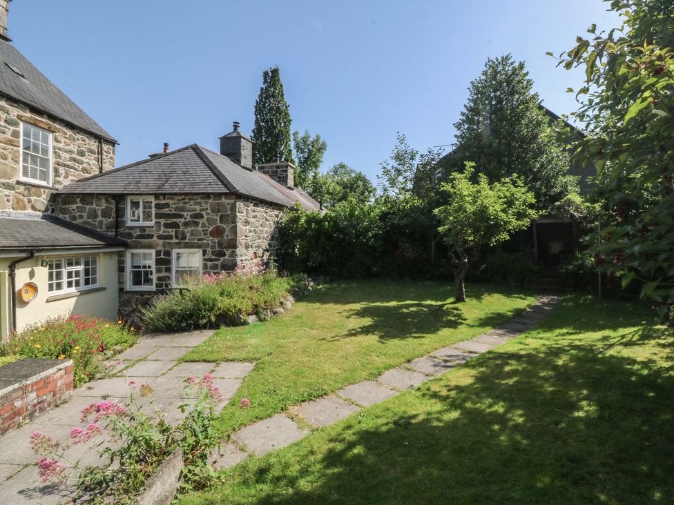 A garden with a stone house and pathway at Tan y Gader in Dolgellau