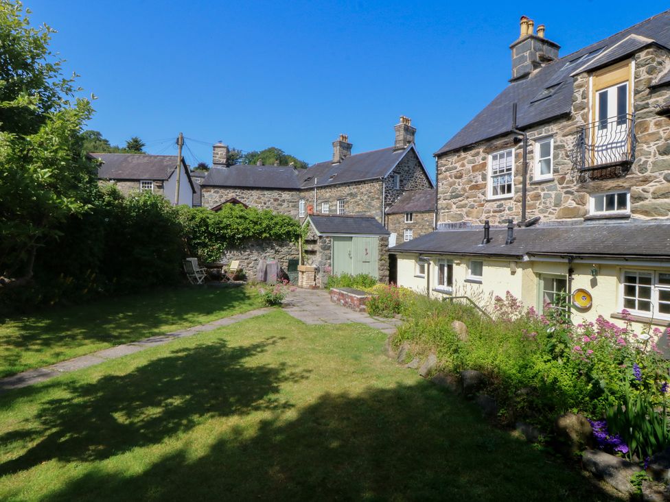 A garden with buildings and a pathway at Tan y Gader in Dolgellau