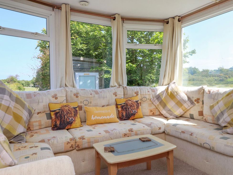 A conservatory with a sofa and cushions at The Lodge in Amlwch