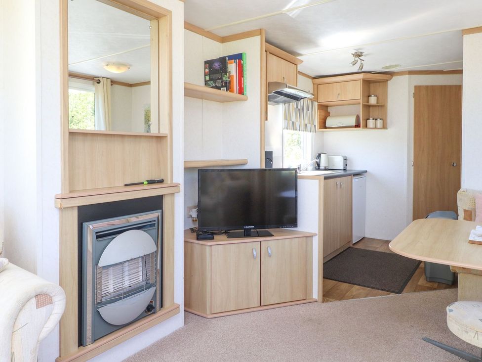 A living room with a television and fireplace at The Lodge in Amlwch