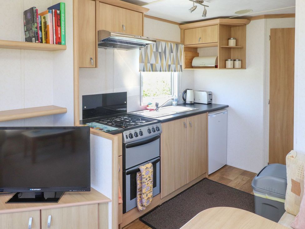 A kitchen with shelves, stove, oven, and refrigerator at The Lodge Amlwch