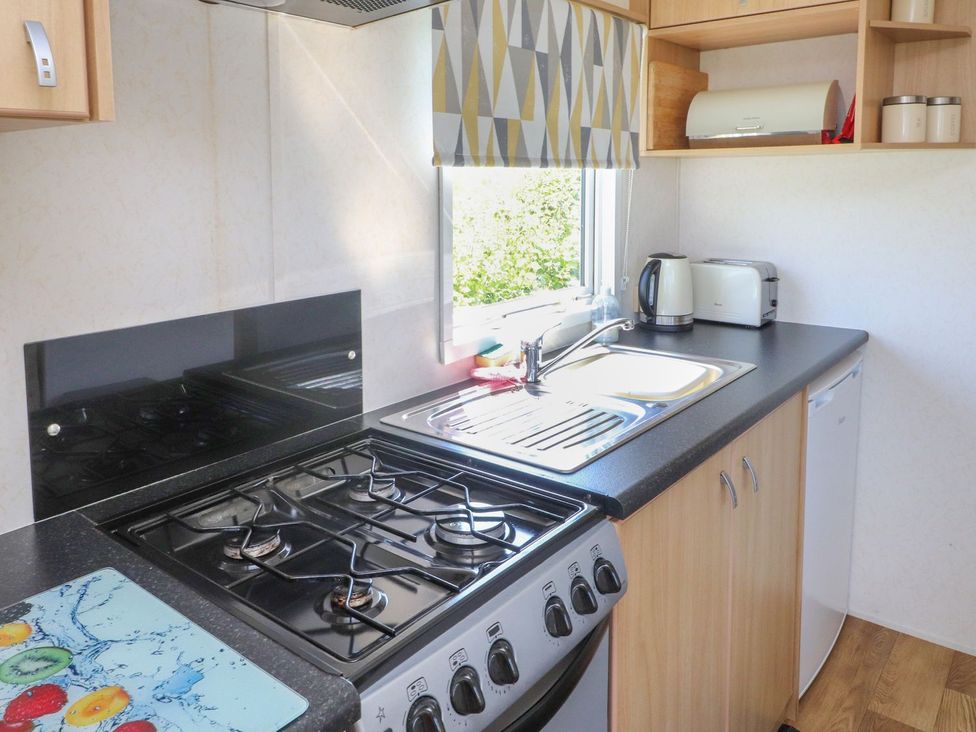 A kitchen with a stove, sink, and kettle at The Lodge in Amlwch