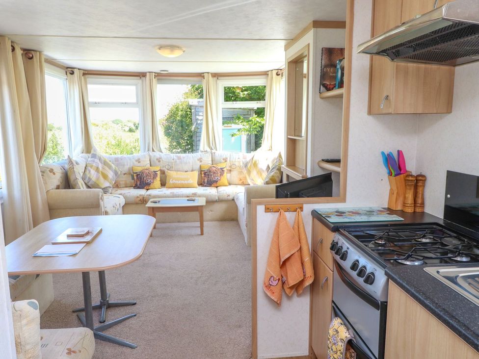 A living room with a sofa and kitchen stove at The Lodge in Amlwch