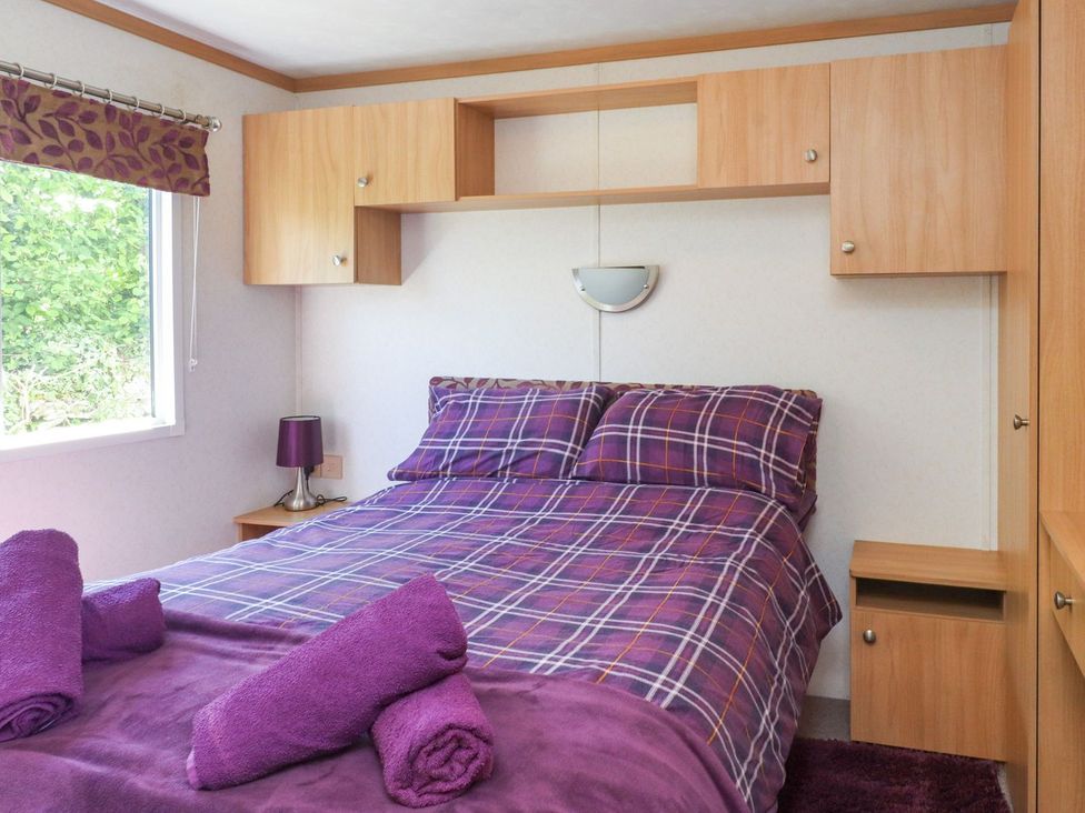 A bedroom with a bed and storage unit at The Lodge Amlwch
