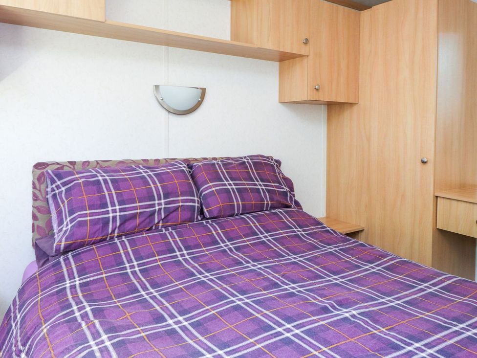A bedroom with a bed and surrounding furniture at The Lodge in Amlwch