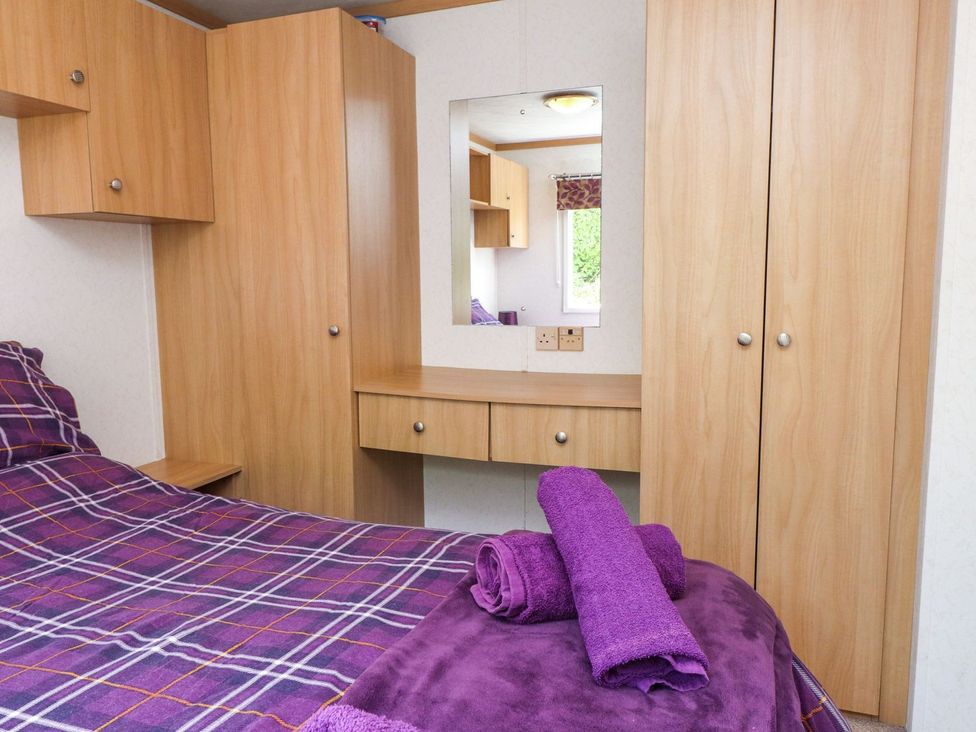 A bedroom with a bed and wooden furniture at The Lodge in Amlwch